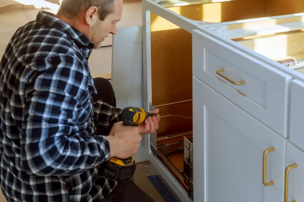 Professional installing kitchen cabinet hardware and hinges with a power drill